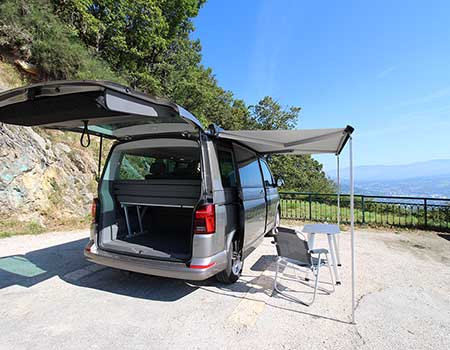 VW California Beach campervan with awning and two chairs